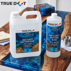 Truedot premium deep pour resin and hardener kit bottles sitting on a glossy blue epoxy river table